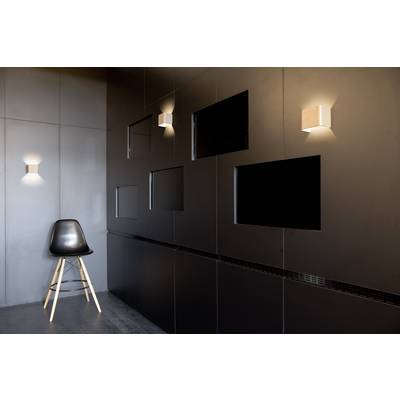 Un fauteuil noir se trouve dans une pièce au design moderne, avec des murs sombres et plusieurs sections murales éclairées.