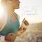 Une femme fait du jogging à l'extérieur au coucher du soleil, portant des écouteurs et des vêtements de sport. Texte : 'Siona Fit', 'Siona XW Fit'.