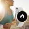 Une femme fait du jogging au coucher du soleil, portant des écouteurs blancs. Au premier plan, une smartwatch affiche un symbole de flammes sur un écran noir.