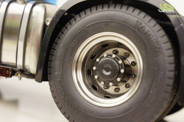 Gros plan d'une roue de camion miniature montrant des jantes détaillées et un pneu portant l'inscription 'Tamiya'.