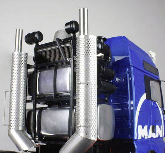 Grand camion bleu avec deux tuyaux d'échappement distinctifs et zone moteur visible, représenté en gros plan.