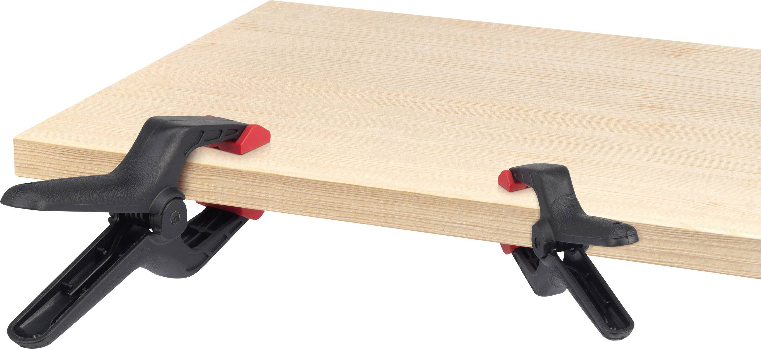 Deux pinces noires avec des poignées rouges maintiennent une planche de bois.