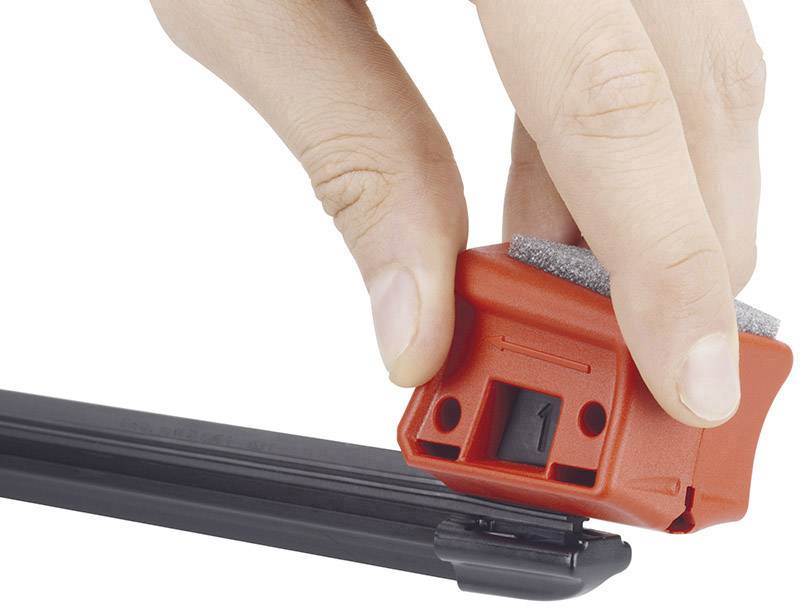 Une main utilisant un aiguiseur rouge sur une patinoire noire. Aiguiseur avec surface de meulage grise.