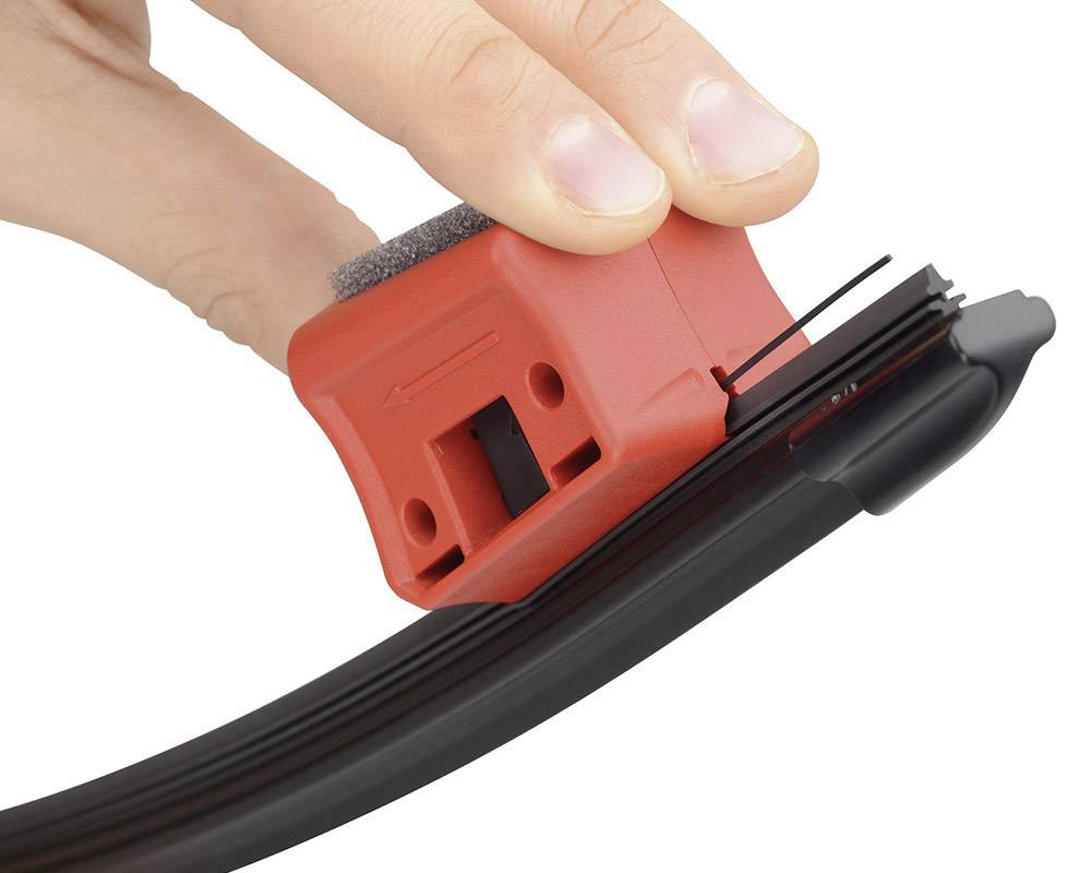 Une main tient un outil rouge pour nettoyer un essuie-glace noir. Une éponge de nettoyage et une flèche sont visibles.