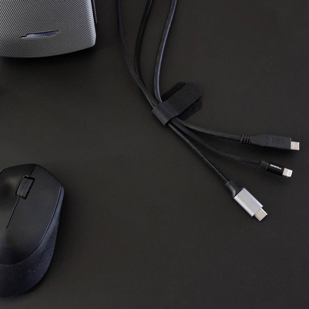 Une souris d'ordinateur sans fil et un hub USB avec trois ports différents sont posés sur un fond noir.