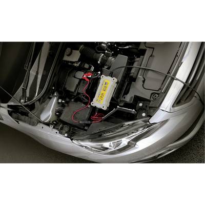 Un capot de voiture ouvert montre un chargeur de batterie automobile connecté, avec des câbles branchés sur la batterie.