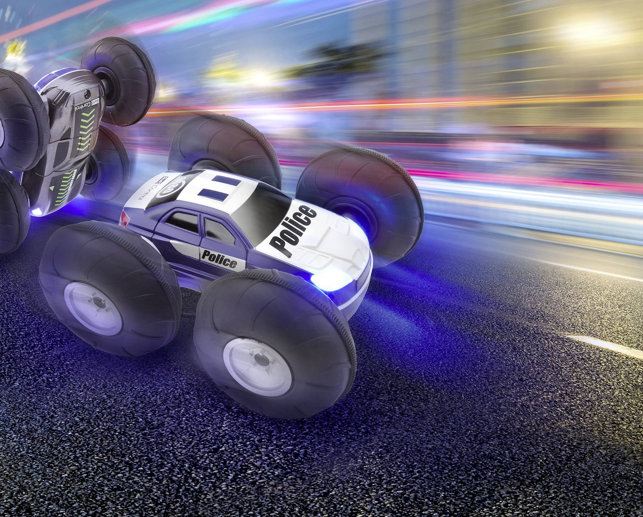 Une voiture télécommandée jouet au design de police, avec de grandes roues, roule rapidement sur une route de nuit, avec des traînées lumineuses en arrière-plan.