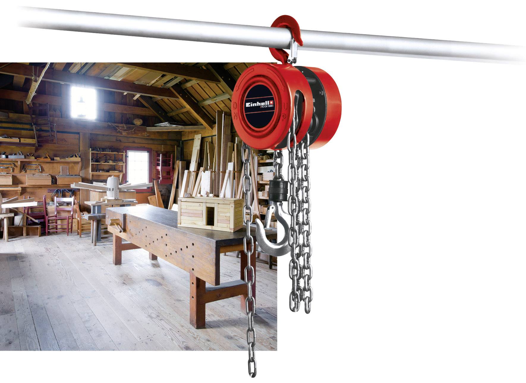 Un dispositif de levage à chaîne rouge est suspendu dans un atelier de menuiserie. À l'arrière-plan, on aperçoit des établis, des outils et des poutres en bois.