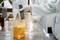Une personne dans un laboratoire mesure le pH d'un liquide orange à l'aide d'un appareil de mesure portable dans un bécher.