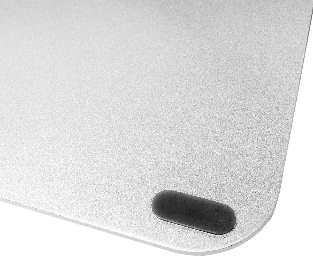 Coin d'un appareil métallique argenté aux bords arrondis avec un coussin antidérapant noir.