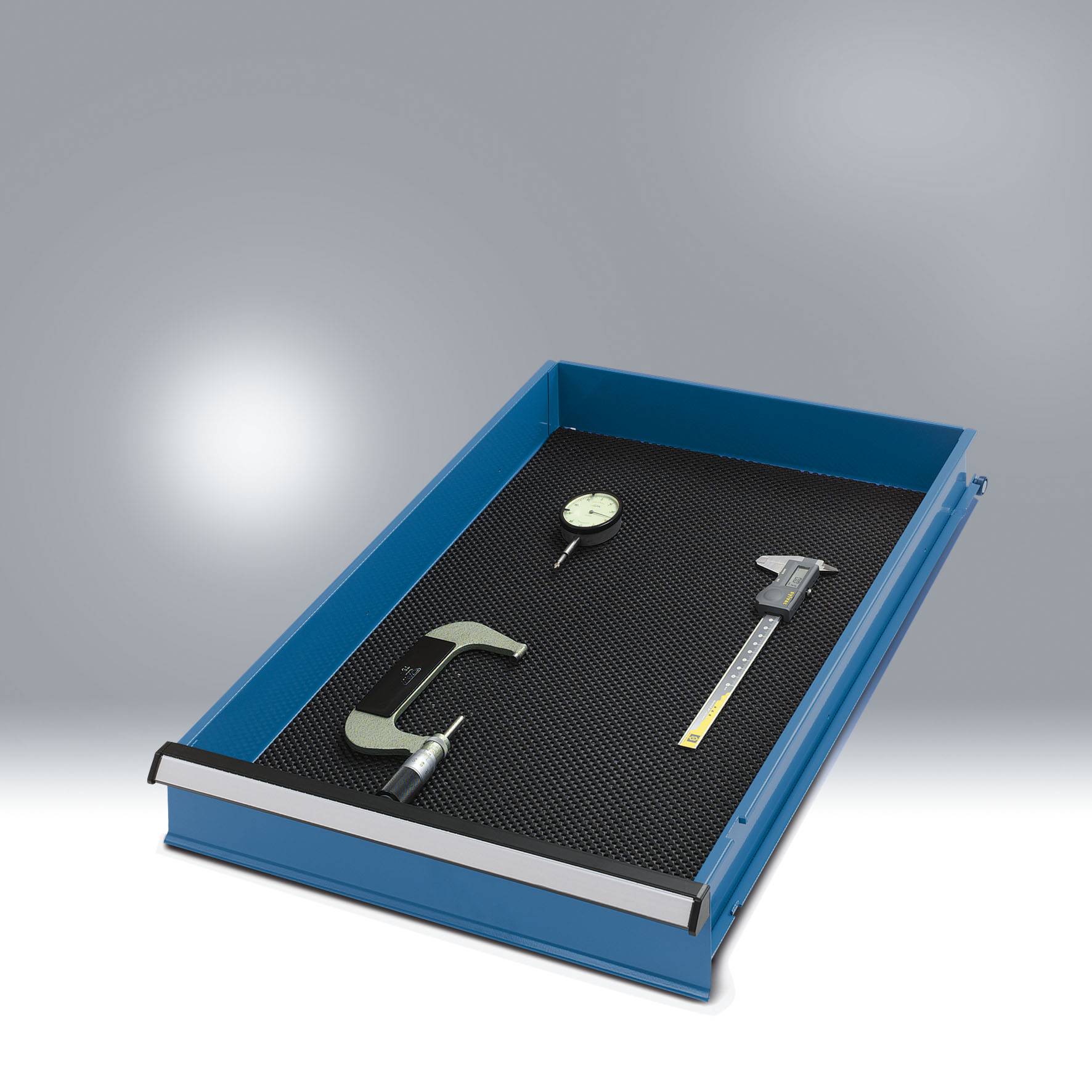 Un tiroir avec un fond noir et plusieurs outils, dont un pied à coulisse et un calibre cylindrique, sur un fond gris.