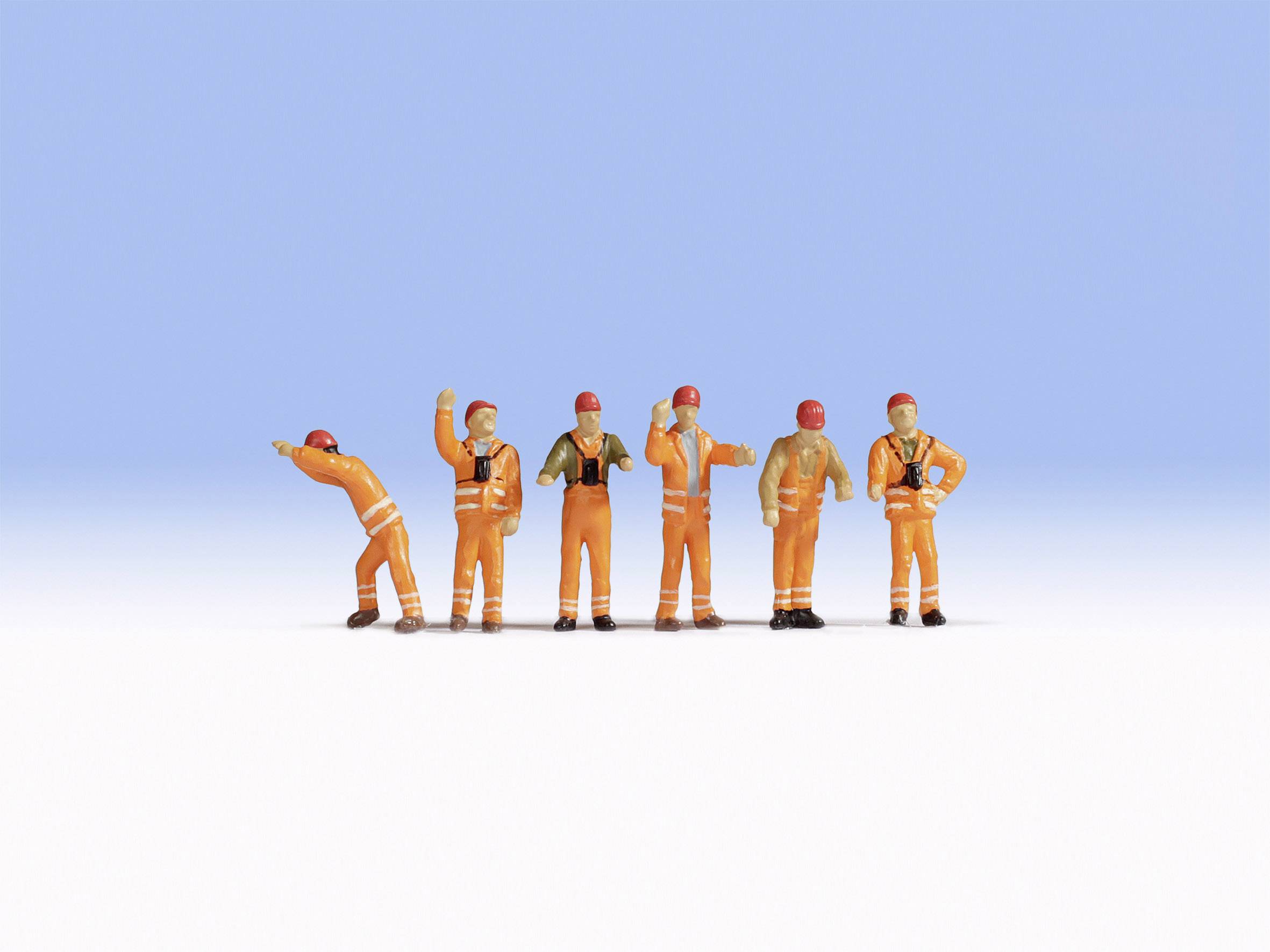 Six petites figurines portant des combinaisons de travail orange et des casques se tiennent devant un fond bleu, comme s'ils travaillaient sur un chantier de construction.