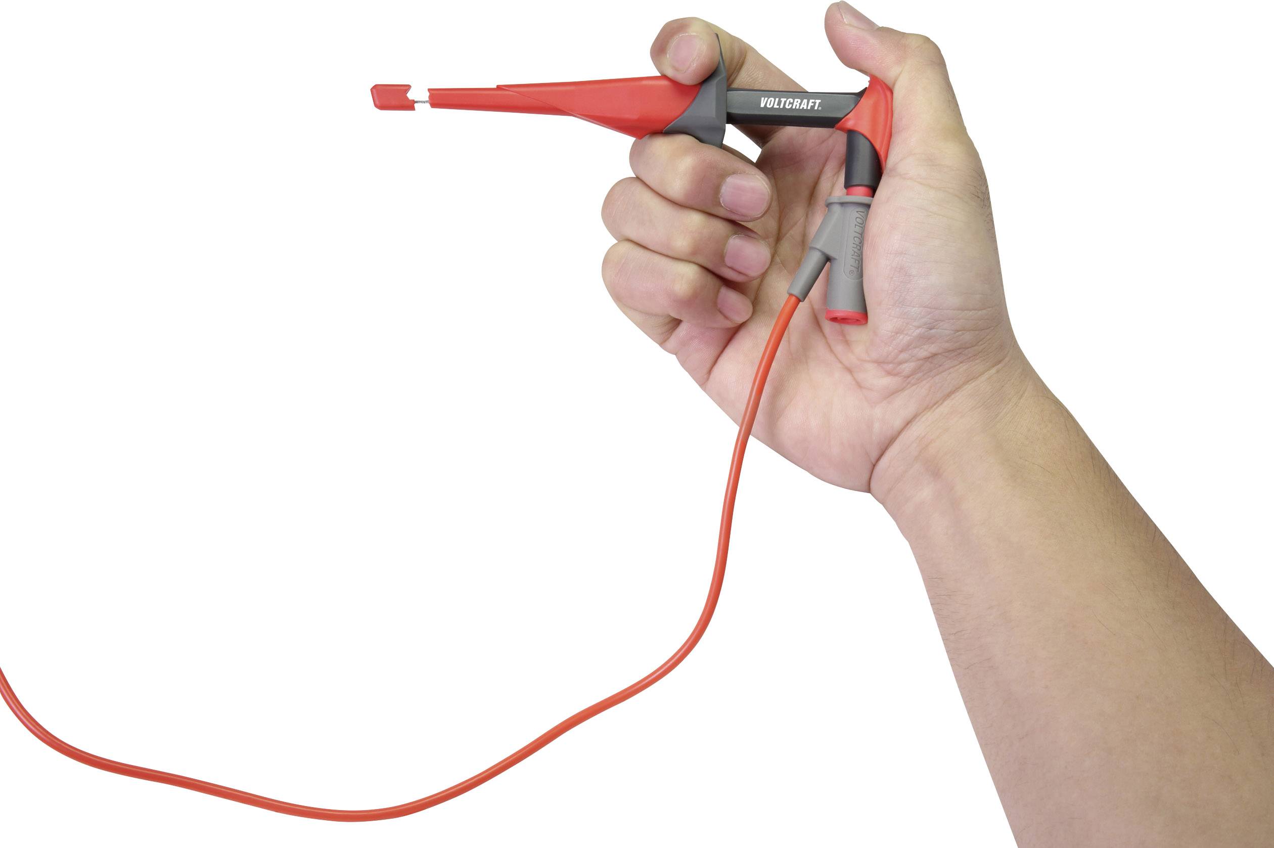 Une main tient une sonde de test électrique rouge avec un long câble, prête à être utilisée dans des applications électriques.