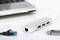 Un hub USB argenté avec trois ports USB et un port Ethernet est posé à côté d'un ordinateur portable. Une clé USB et un câble Ethernet sont placés à proximité.