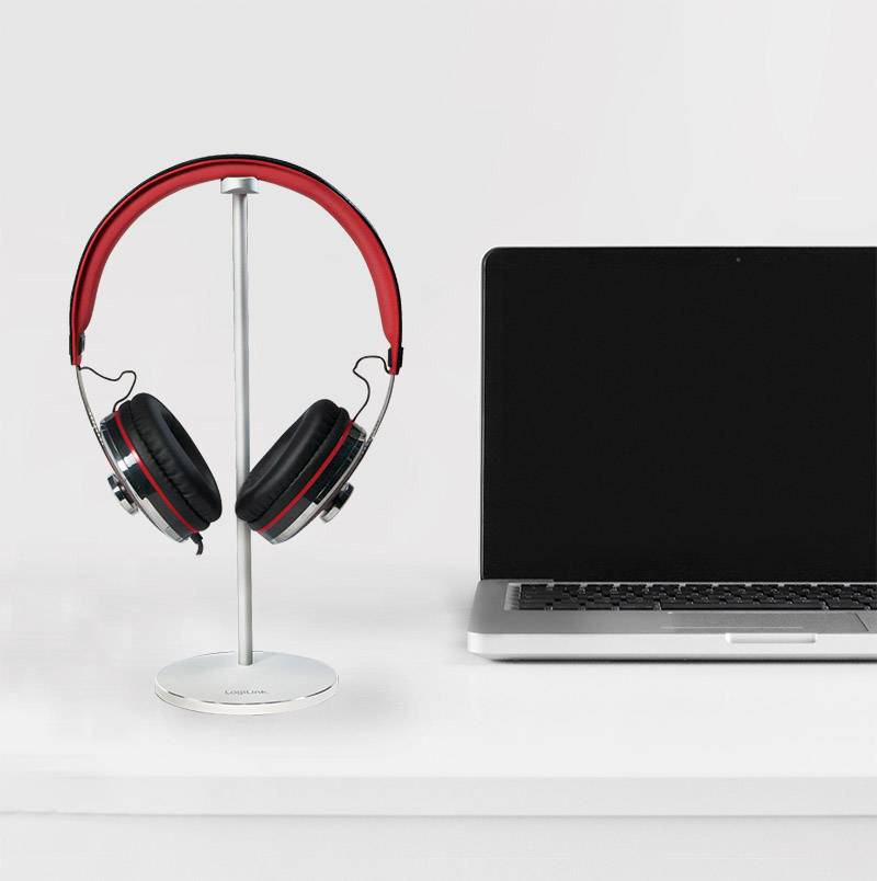 Casque audio avec arceau rouge posé sur un support, à côté d'un ordinateur portable fermé.