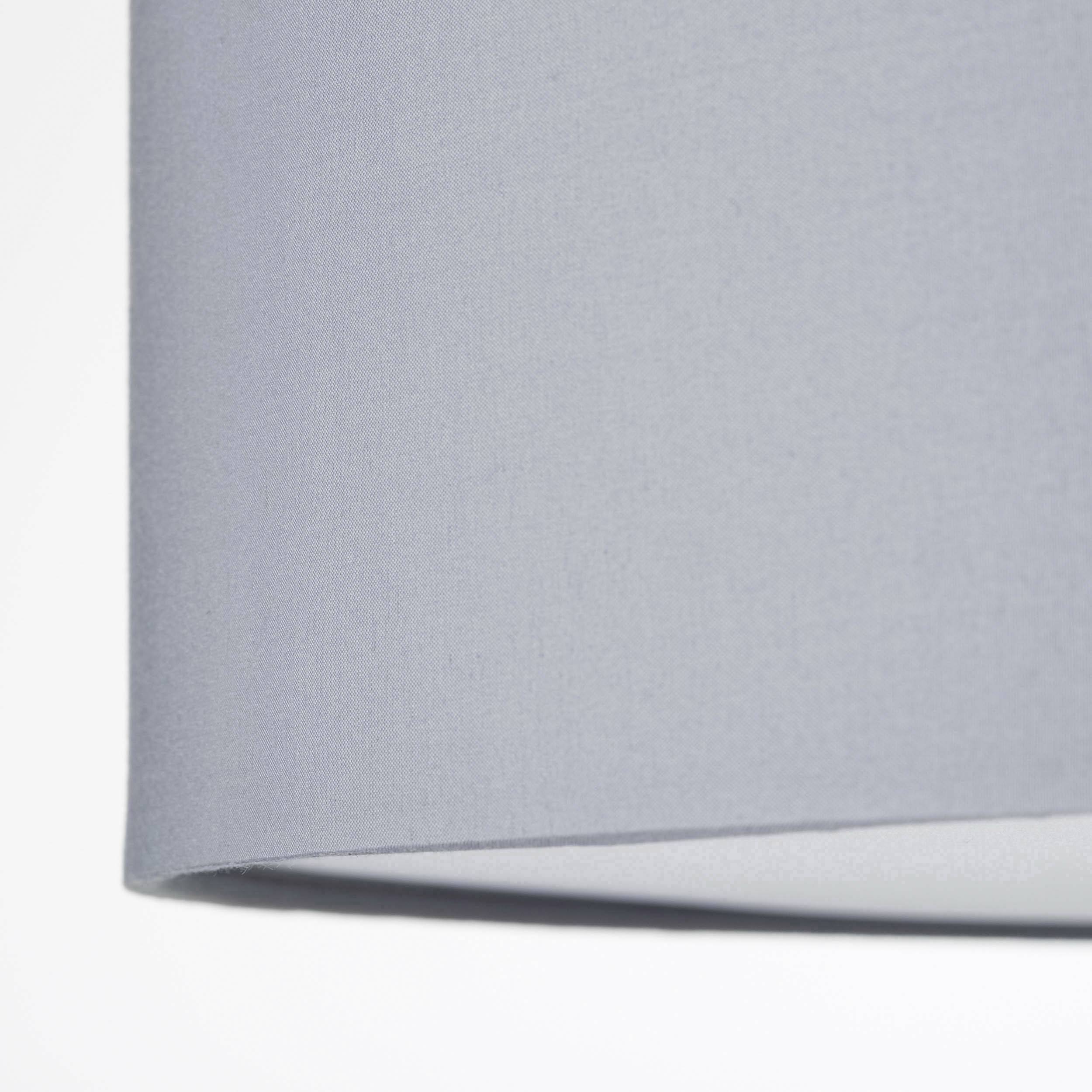 Une lampe en tissu gris à l'esthétique épurée et moderne, suspendue contre un fond blanc.
