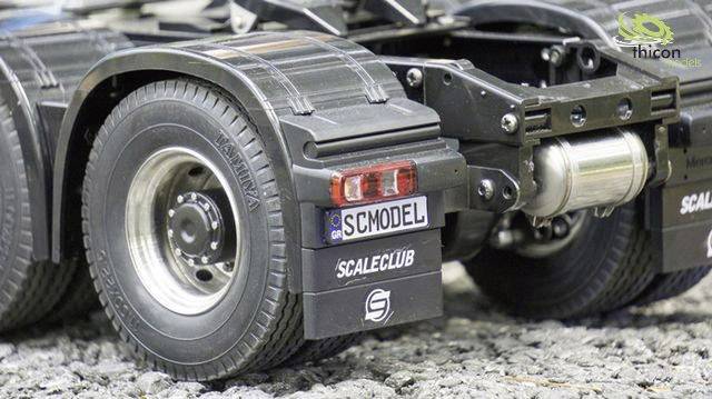 Gros plan sur l'arrière d'un camion-modèle portant la plaque d'immatriculation 'SCMODEL'. L'arrière-plan présente une surface rocheuse.