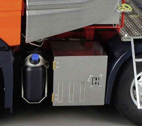 'Gros plan sur un camion : Coffre à outils latéral en métal à côté d'un conteneur noir situé sous la cabine du conducteur.'