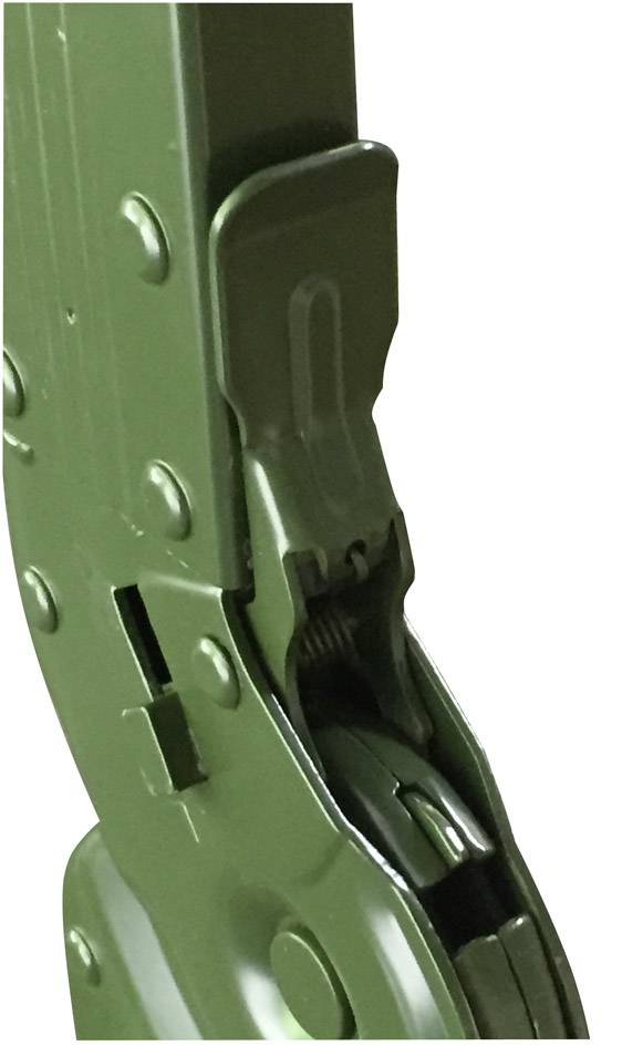 Un fermoir vert en métal sur un outil, probablement un levier ou un mécanisme de serrage, avec une charnière et un ressort visibles.