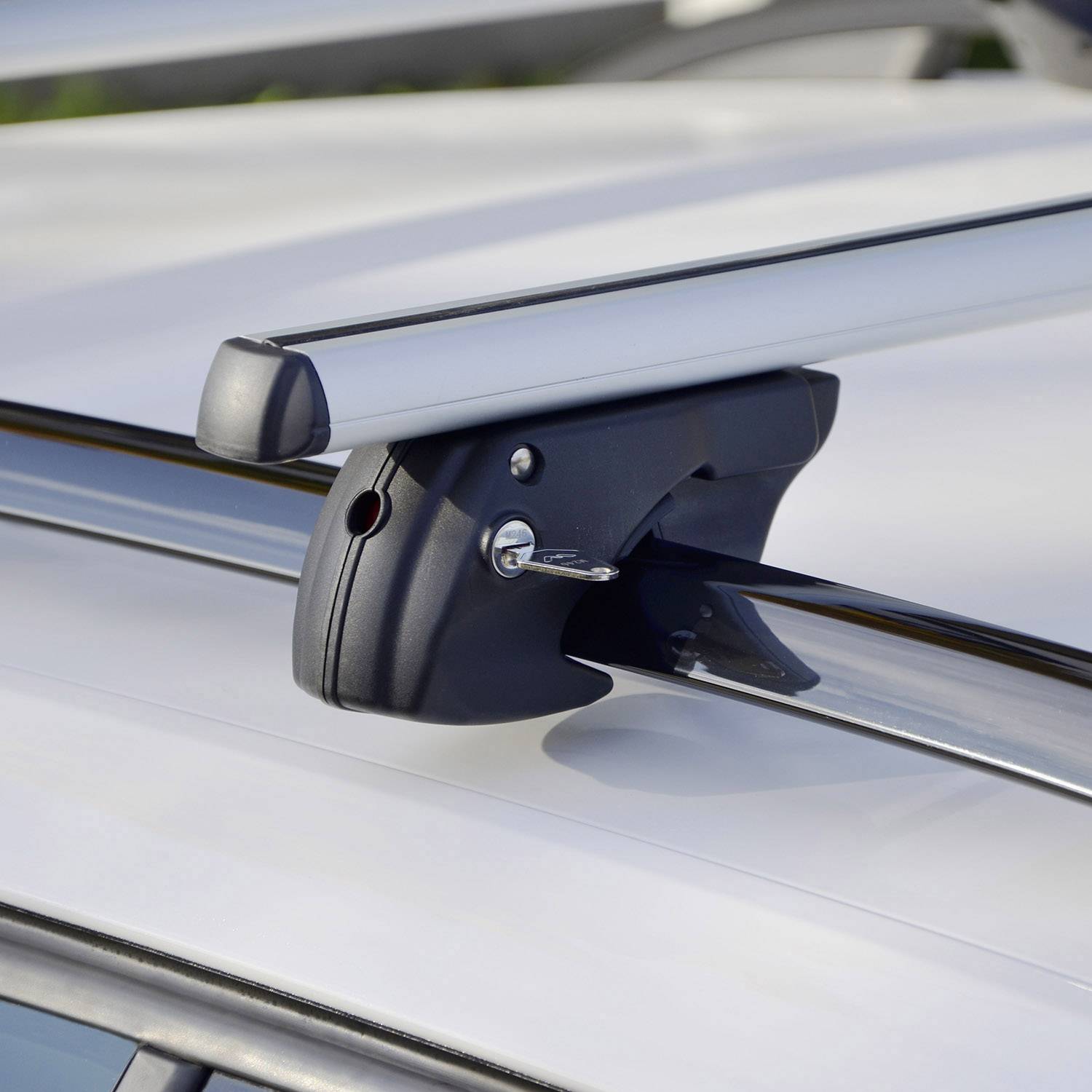 Un porte-bagages de toit avec un verrou, monté sur le toit du véhicule. La clé est insérée dans le verrou. Adapté pour le transport de charges.
