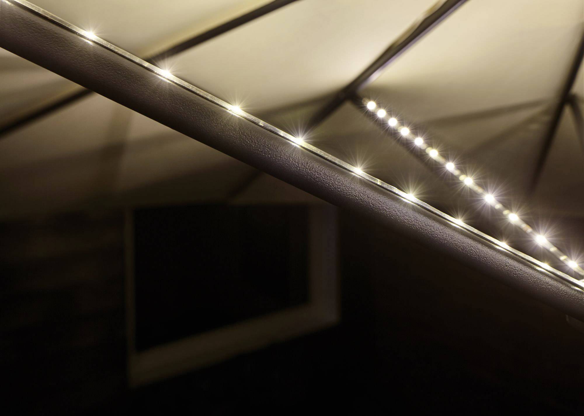 Guirlande lumineuse fixée sur un auvent incliné, diffusant une lueur douce dans une pièce sombre.