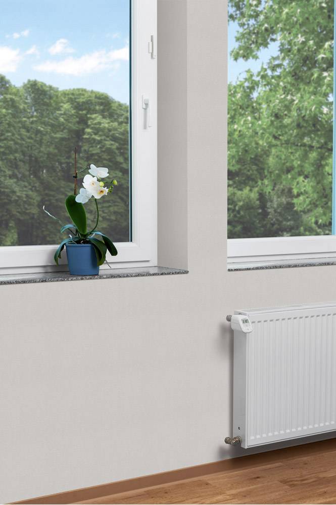 Un orchidée dans un pot bleu est posée sur un rebord de fenêtre. À travers la fenêtre, on aperçoit des arbres verts et un ciel bleu.