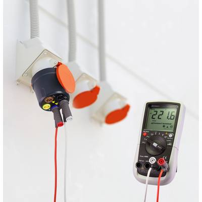 Un multimètre mesure une tension de 22,16 V à une prise électrique multiconnexion. L'affichage est numérique.