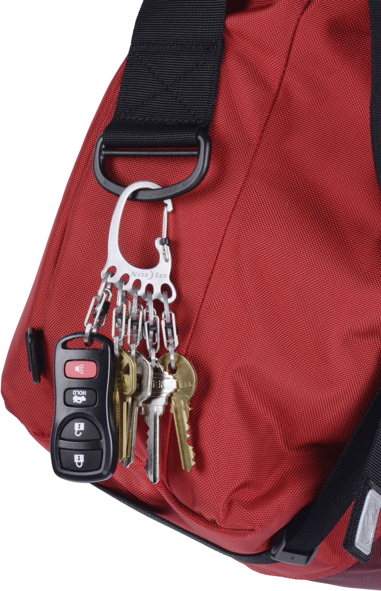 Un sac à dos rouge avec plusieurs clés et un porte-clés de voiture suspendu à une boucle métallique.