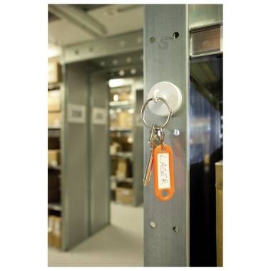 Un porte-clés portant l'inscription 'Stock' est accroché à une étagère métallique. En arrière-plan, on peut voir des étagères chargées de cartons.