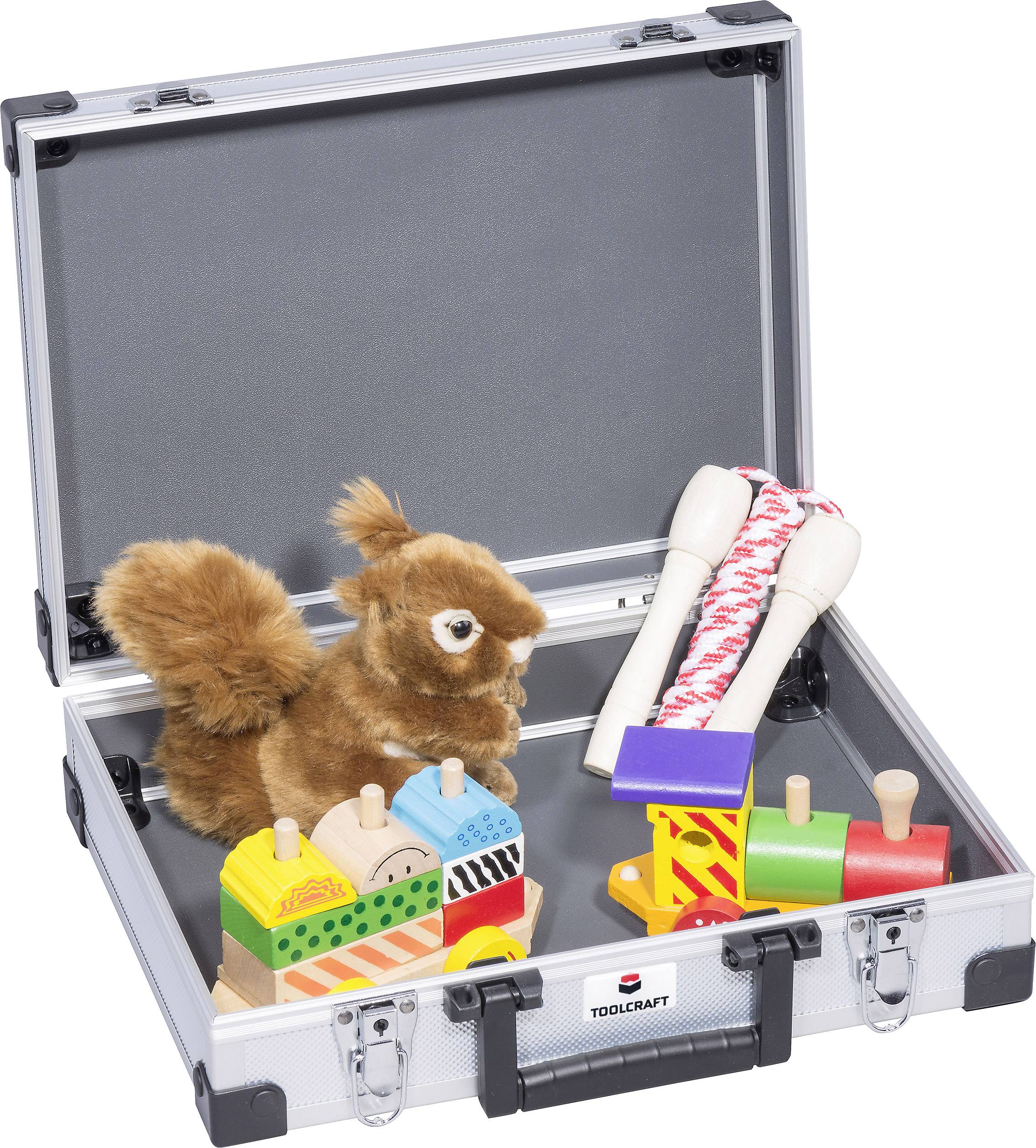 Une valise métallique ouverte contenant des jouets : un écureuil en peluche, un train en bois et des blocs de construction colorés en bois.