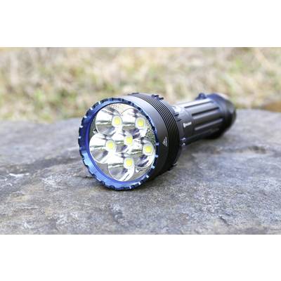 Une lampe de poche à six LED lumineuses est posée sur un rocher en extérieur.