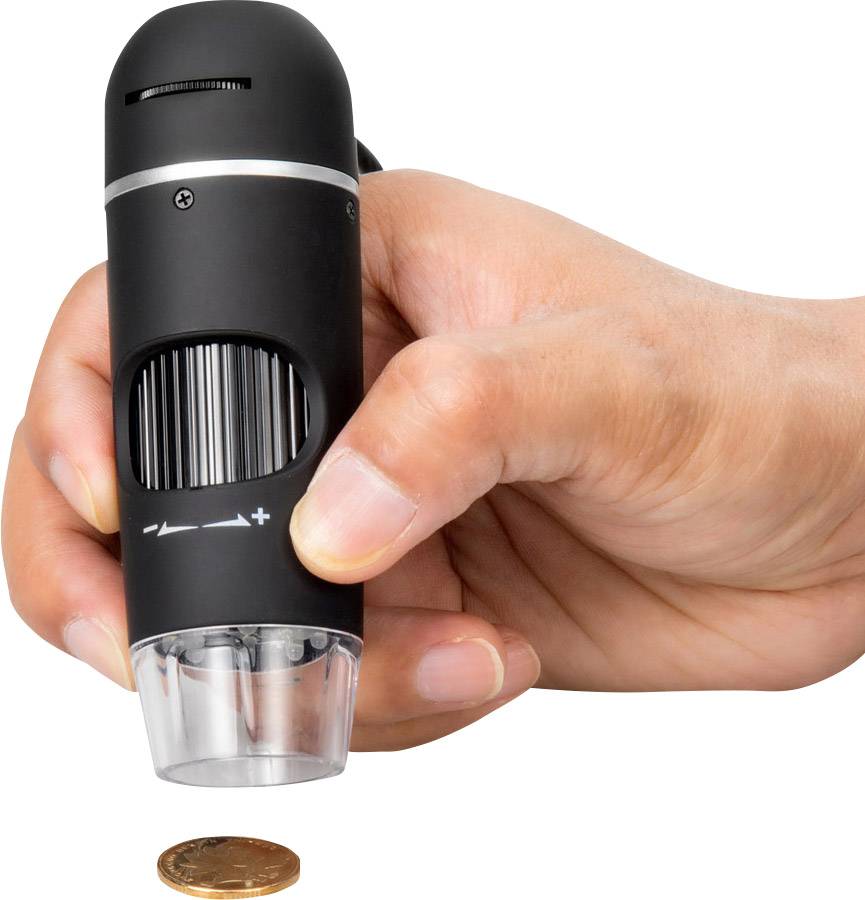 Une main tient un microscope compact au-dessus d'une pièce de monnaie sur un fond blanc, afin de grossir les détails de la pièce.