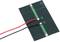 Une petite cellule solaire verte avec deux fils soudés, l'un rouge et l'autre noir, montre les connexions pour le flux électrique.