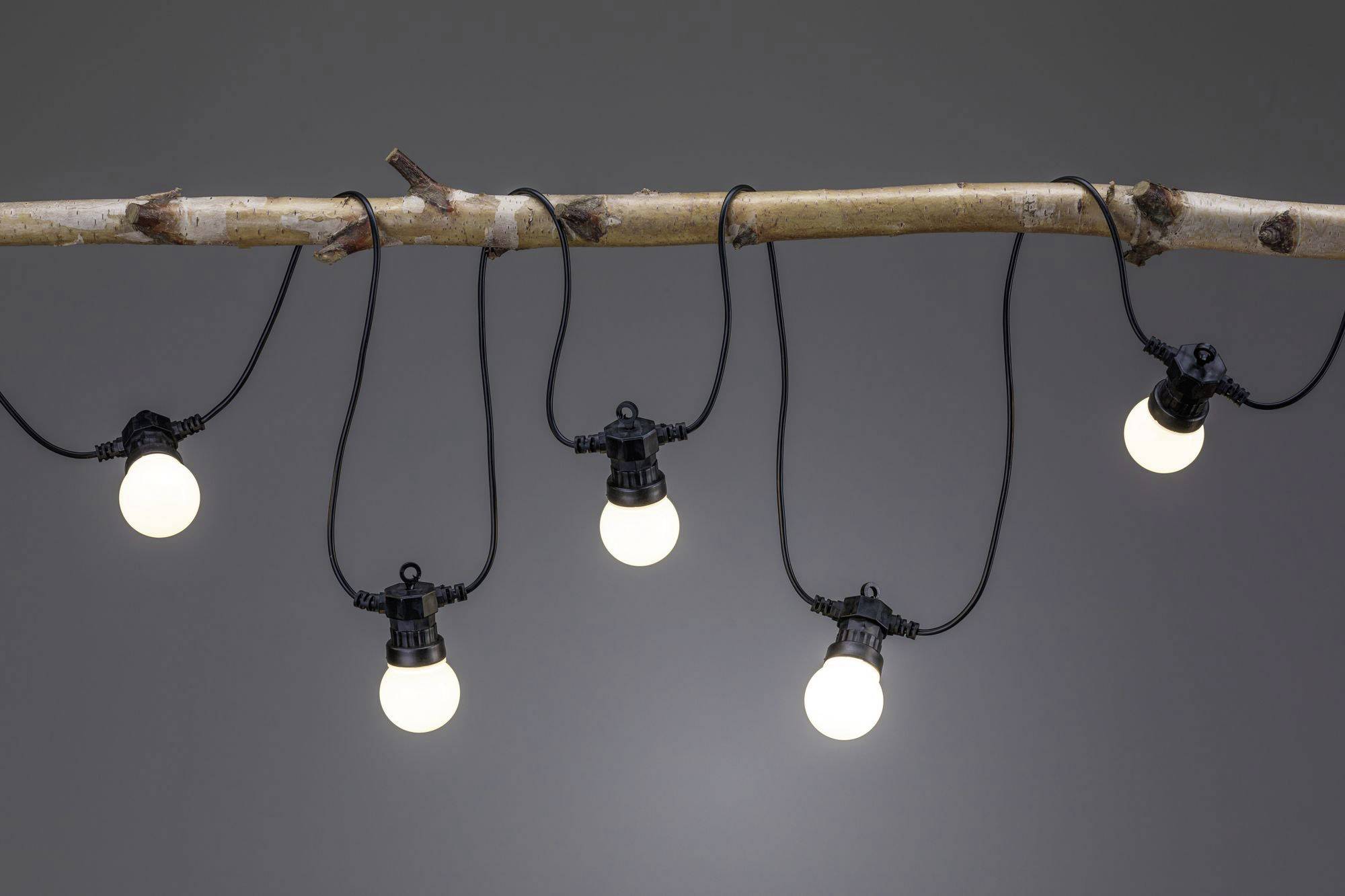 Une tige en bois est suspendue horizontalement avec cinq ampoules lumineuses, réparties de manière uniforme, accrochées à des câbles noirs.