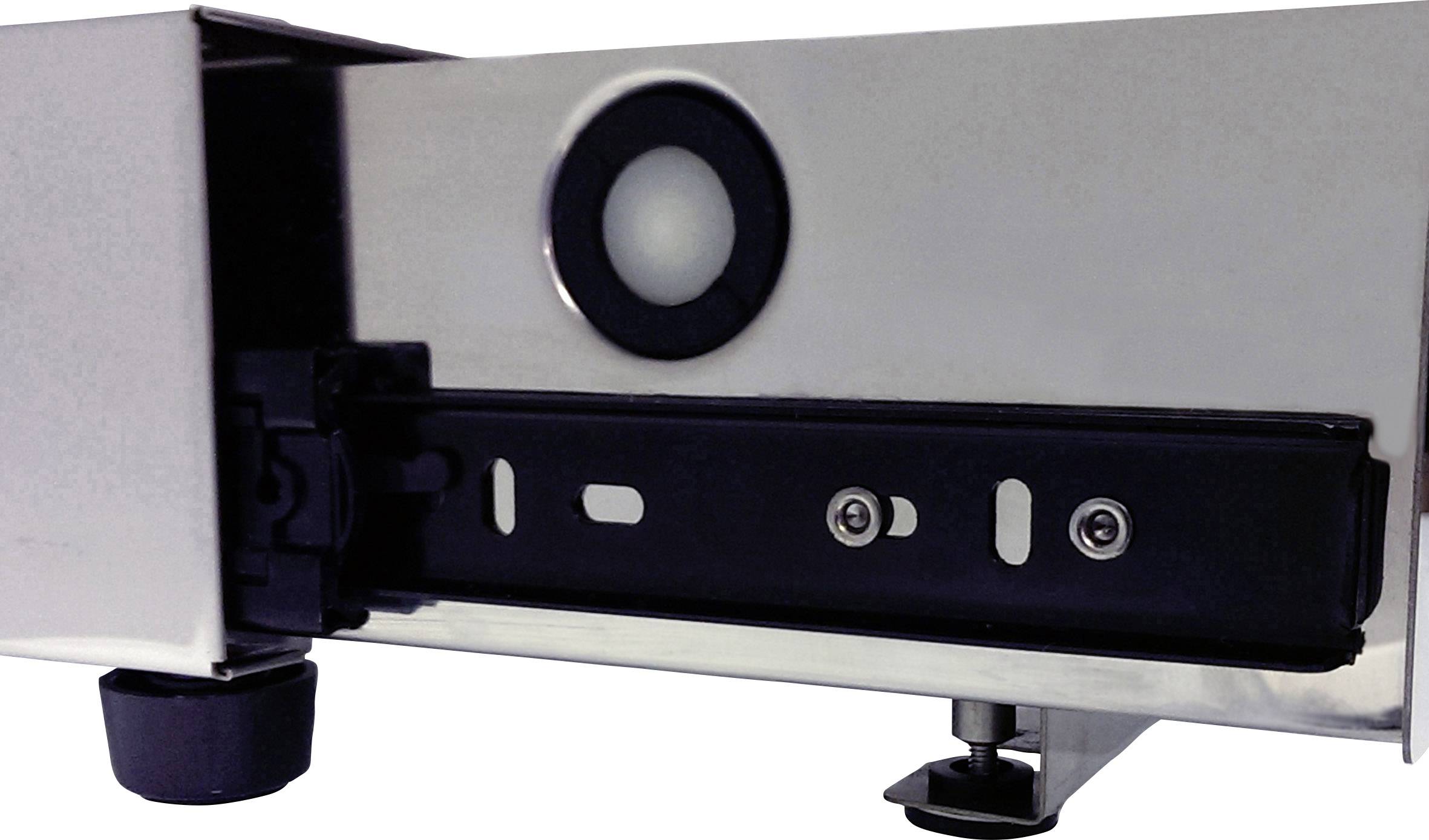 Gros plan d'un tiroir métallique, probablement partie d'un placard ou d'un appareil. À gauche, un pied support arrondi, au-dessus un évidement circulaire.