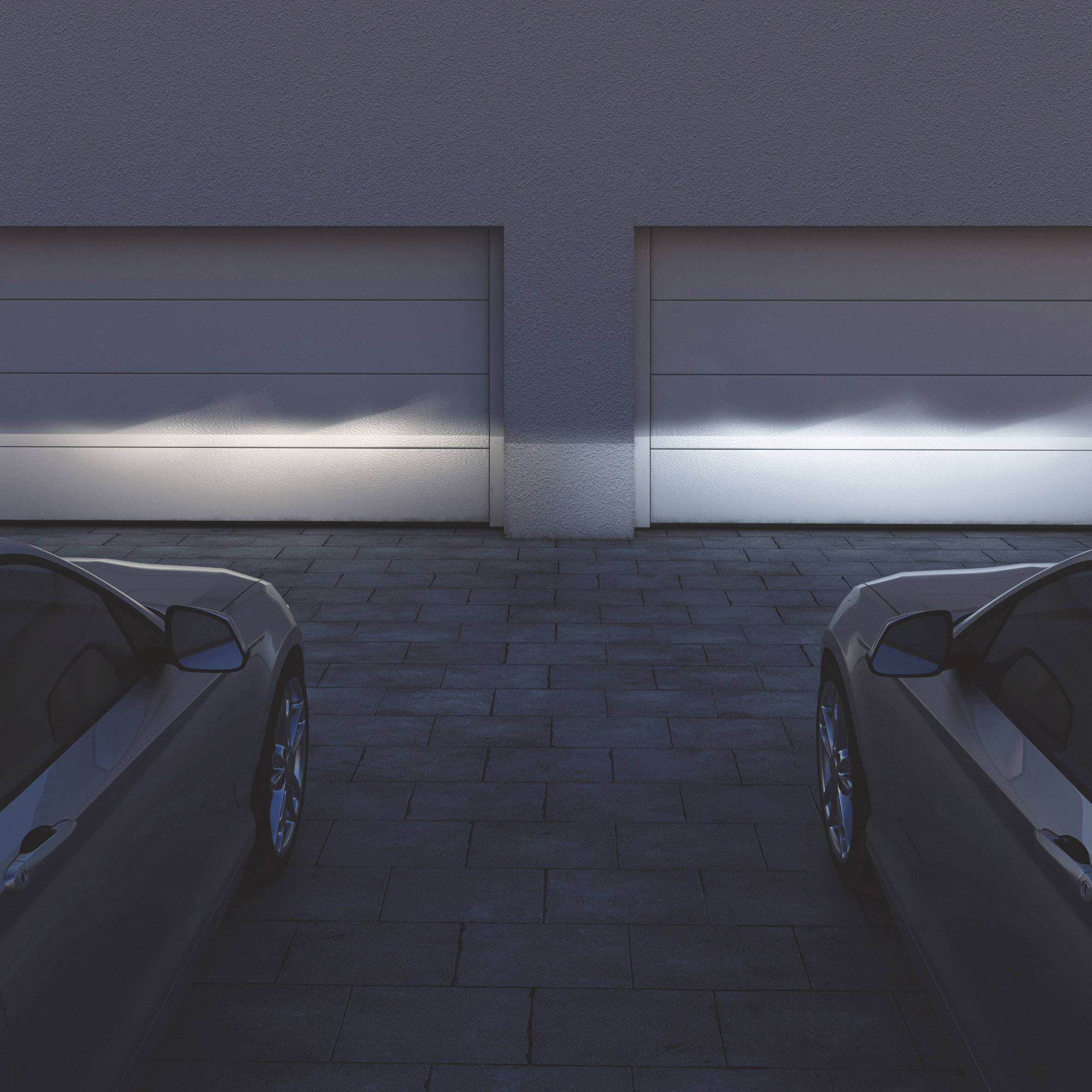 Deux voitures stationnées devant des portes de garage fermées dans une allée sombre. Les deux voitures sont partiellement visibles.