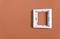 Cadre d'interrupteur vide et blanc sur un mur orange, sans éléments de commutation.