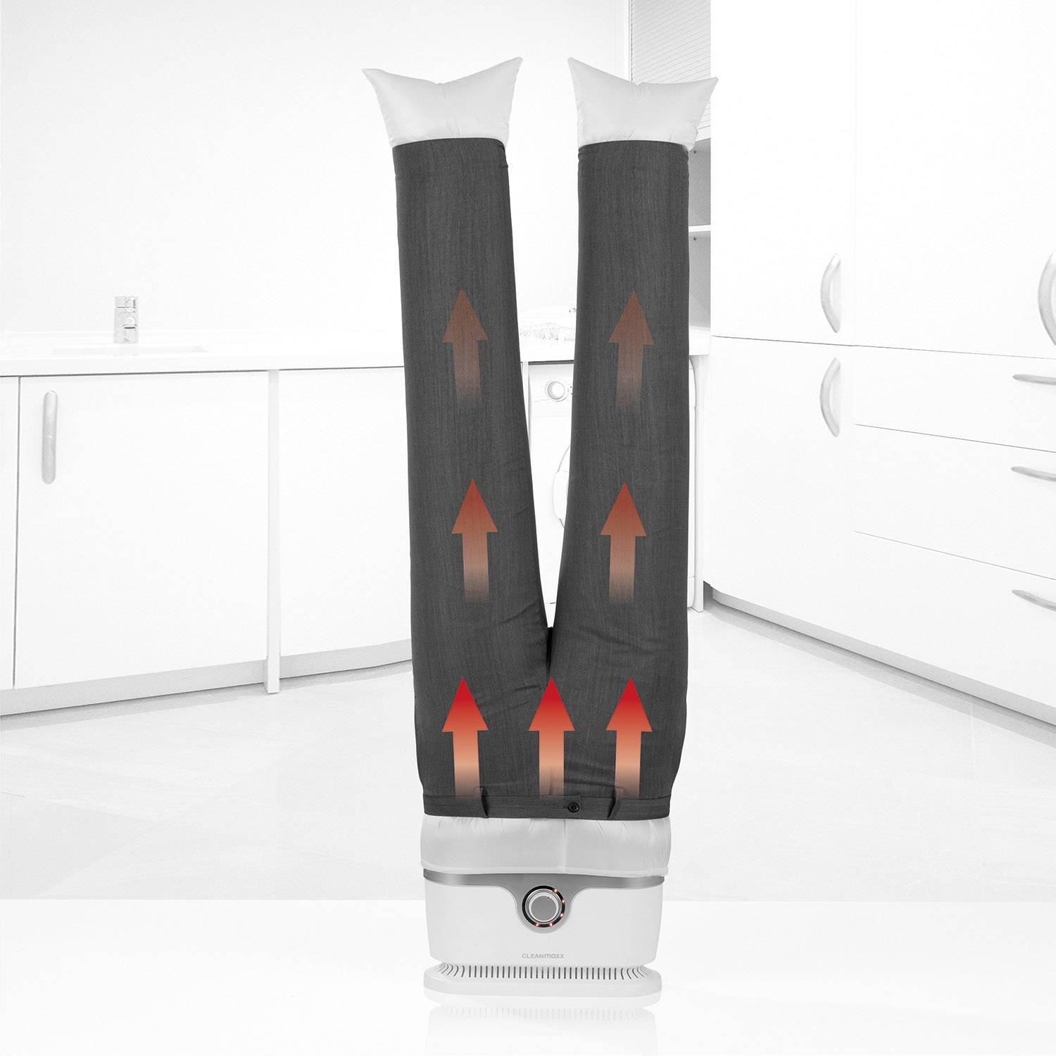 Un appareil sèche deux jambes de pantalon gris dans une cuisine en faisant circuler de l'air chaud ascendant.