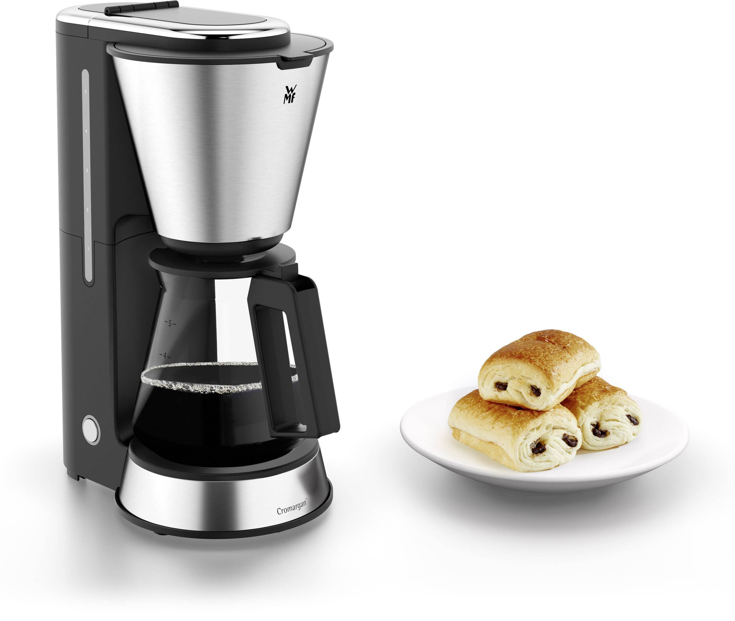 Une machine à café argentée à côté d'une assiette contenant trois croissants au chocolat.