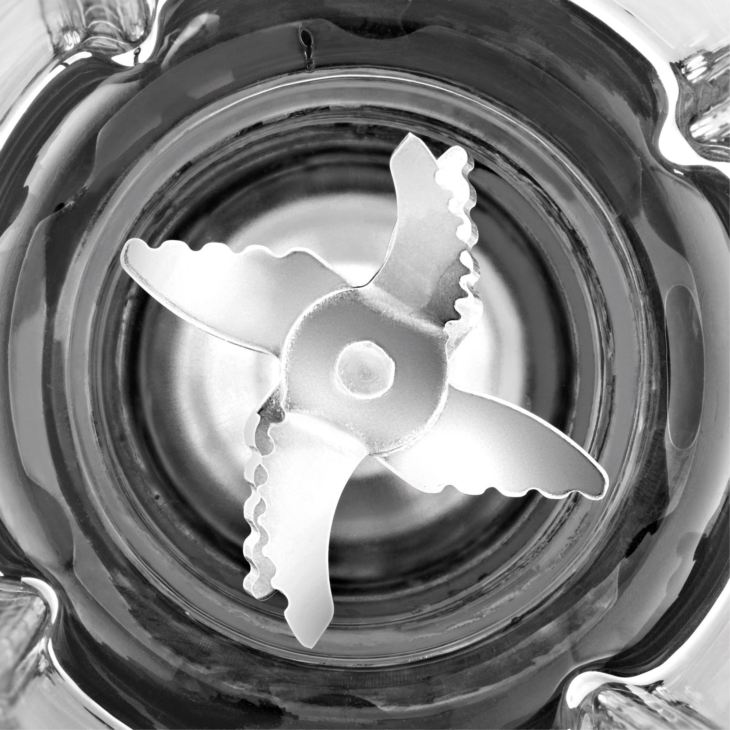 Un regard de haut sur les lames d'un mixeur dans un récipient en verre, qui semblent tranchantes et robustes ; le mixeur est vide.