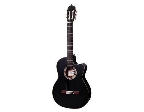 Guitare acoustique noire à six cordes, surface satinée et forme classique, posée contre un fond blanc.