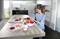 Une femme fait de la pâtisserie dans une cuisine moderne. Sur le plan de travail sont disposés des ingrédients tels que des œufs, de la farine, des baies et du lait.
