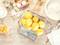 Des citrons dans un bol en verre posés sur une balance de cuisine numérique affichant 768 grammes, entourés d'ingrédients de pâtisserie.