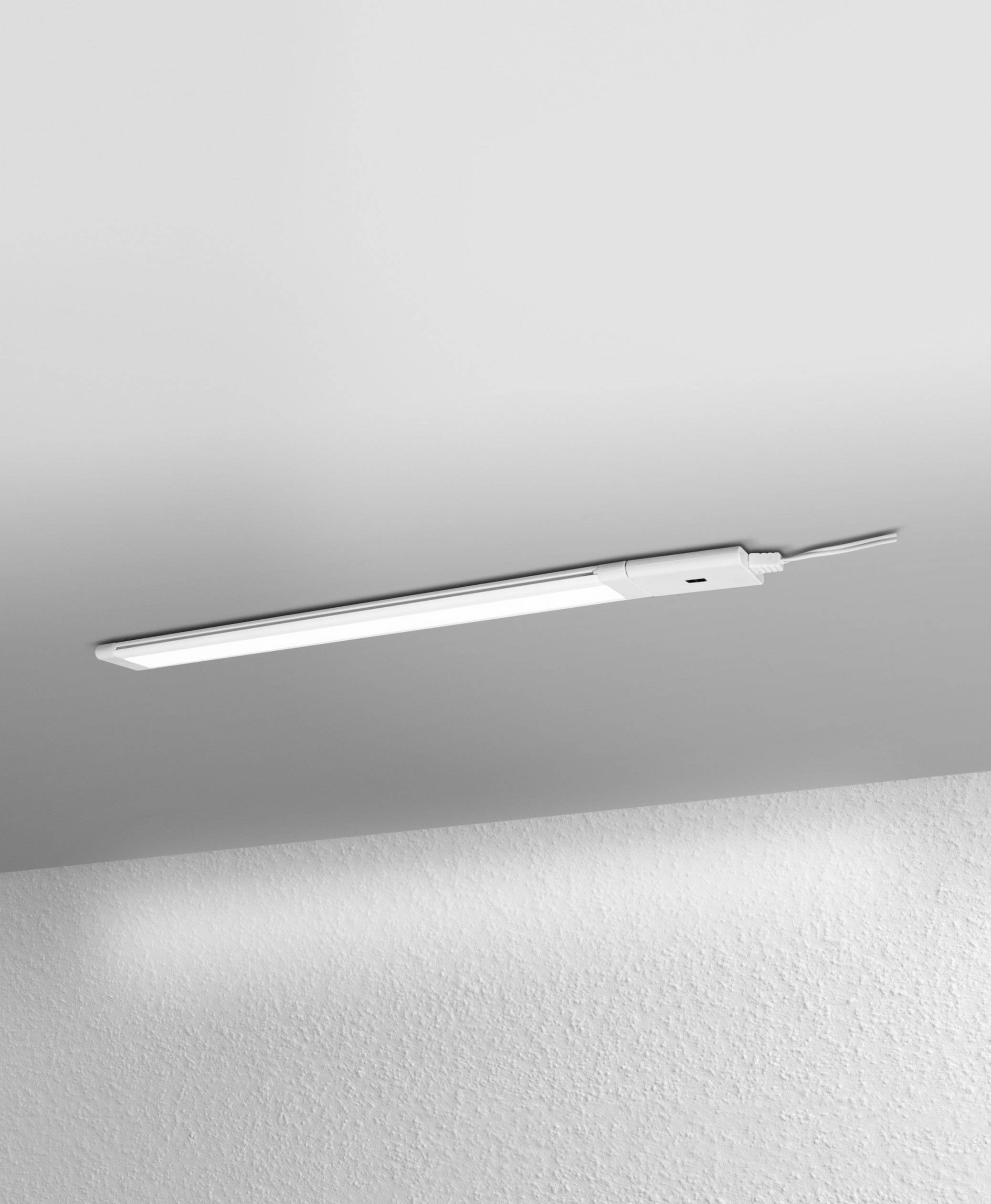 Une mince lampe LED est montée au plafond blanc, assurant un éclairage uniforme, avec les câbles visibles sur le côté.