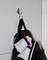 Un sac à dos noir est accroché à un crochet. Des baskets blanches avec des rayures roses dépassent du sac à dos.