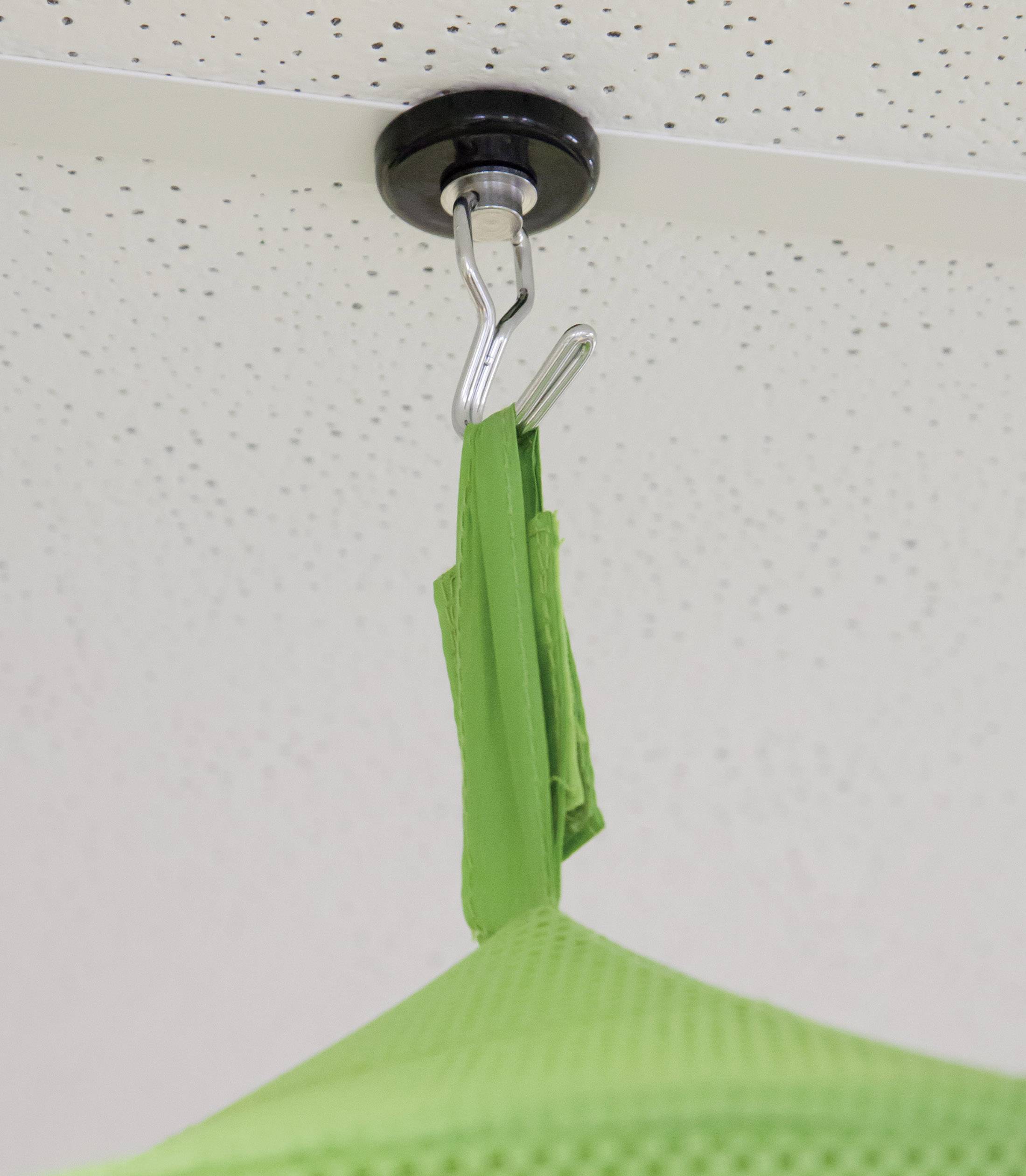Fauteuil suspendu vert fixé au plafond. Il est accroché à un crochet et sert de siège pour se détendre.