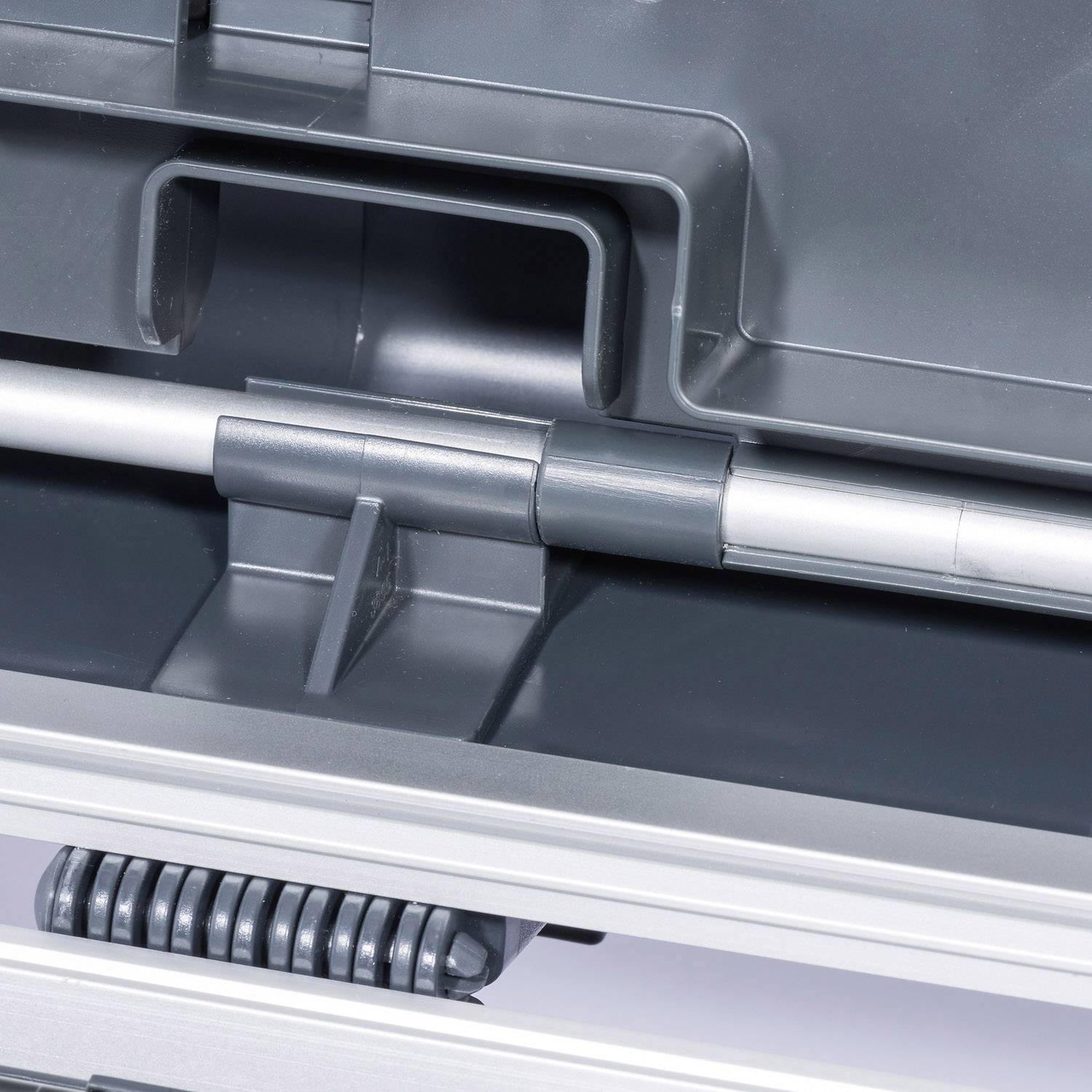 Gros plan d'une charnière métallique argentée d'une machine ou d'un meuble ouvert, entourée de pièces en plastique gris.