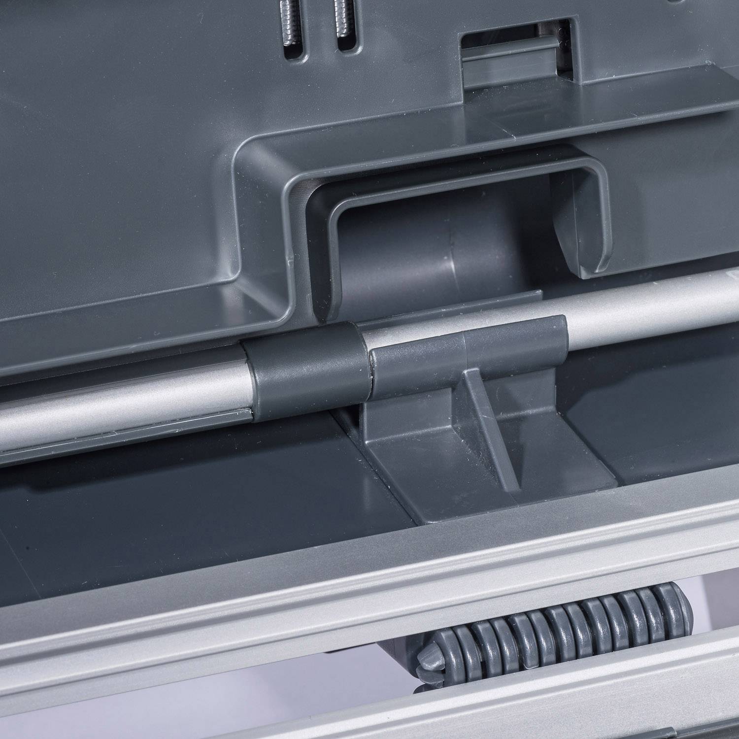 Gros plan sur une construction en plastique gris avec des roues et des rails métalliques, probablement un élément d'un dispositif industriel ou technique.