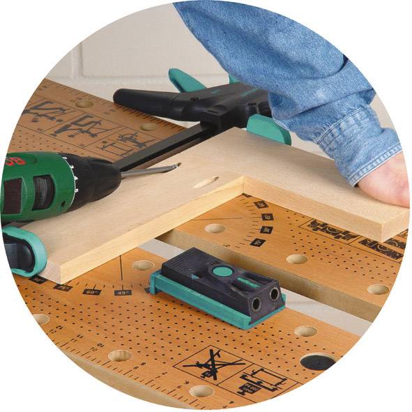 Une personne travaille avec un visseuse sans fil sur une planche de bois posée sur un établi. Divers outils sont visibles.