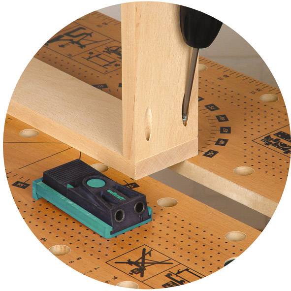 Assemblage de bois utilisant la technique des chevilles en bois sur un établi. Des outils et des instruments de mesure sont utilisés.